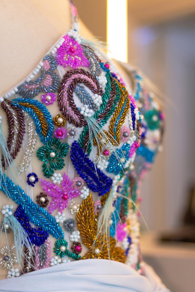 Detailed close-up of colorful beaded embroidery on fabric, showcasing intricate craftsmanship in fashion design.